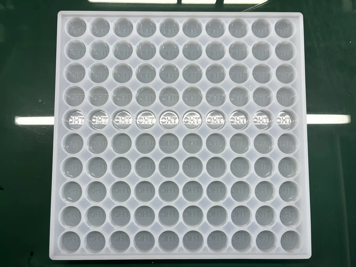 White silicone gummy tray with round cavities, some filled for sample check