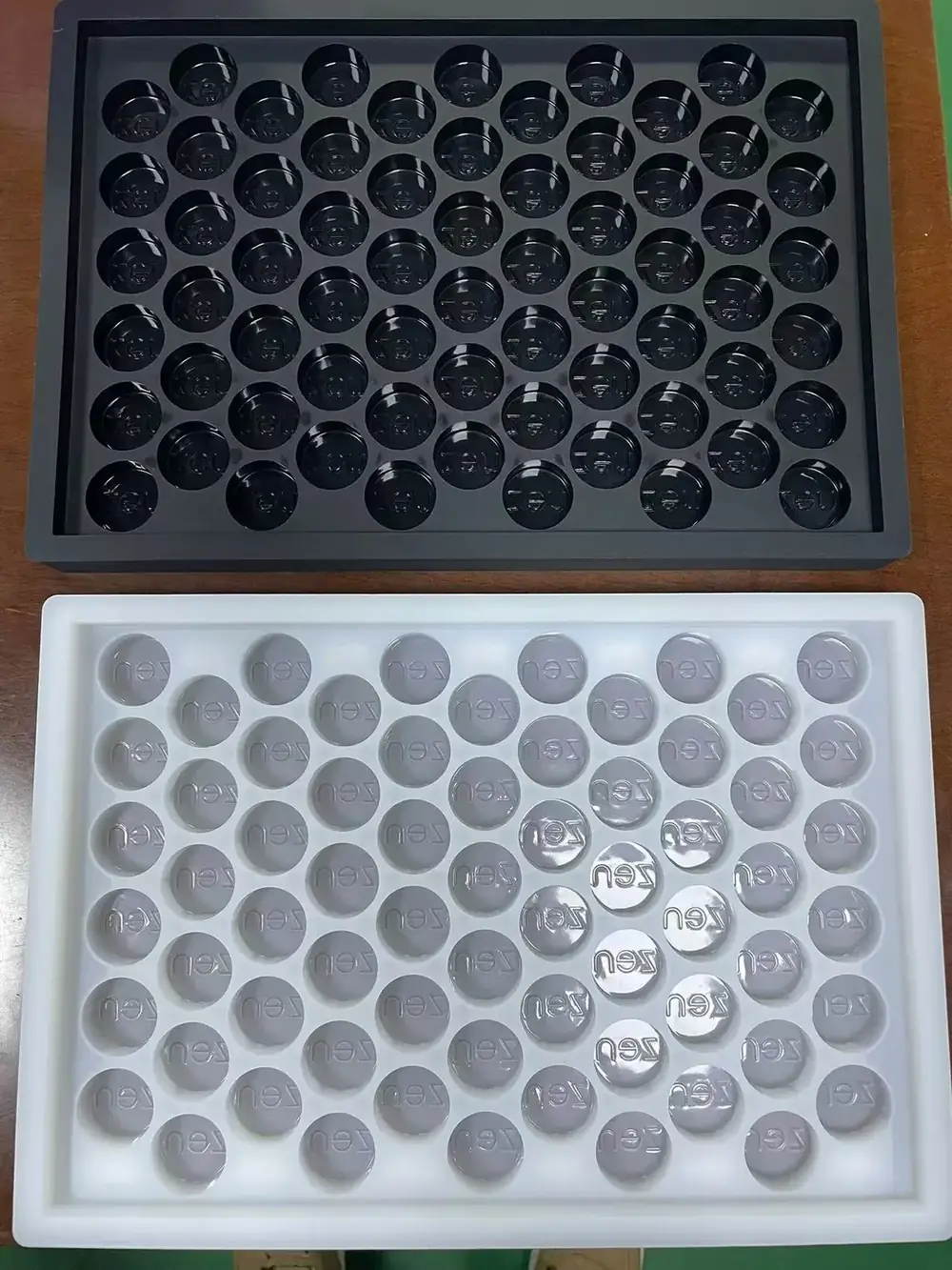 Black and white silicone gummy trays with round cavities and customer face marks