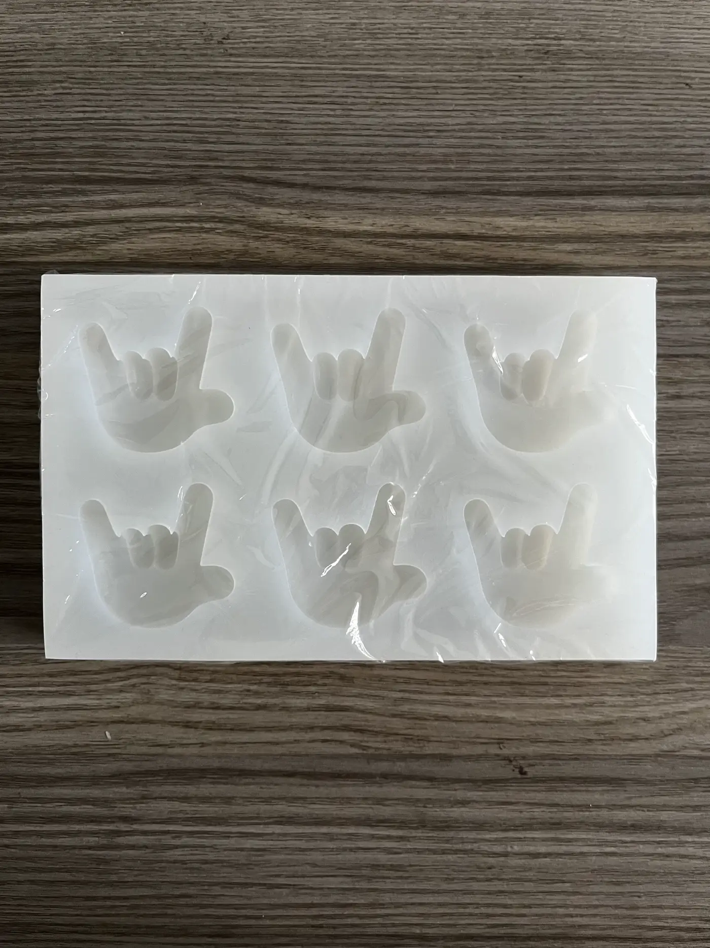 White silicone mold with six ILY hand cavities, still in pack film