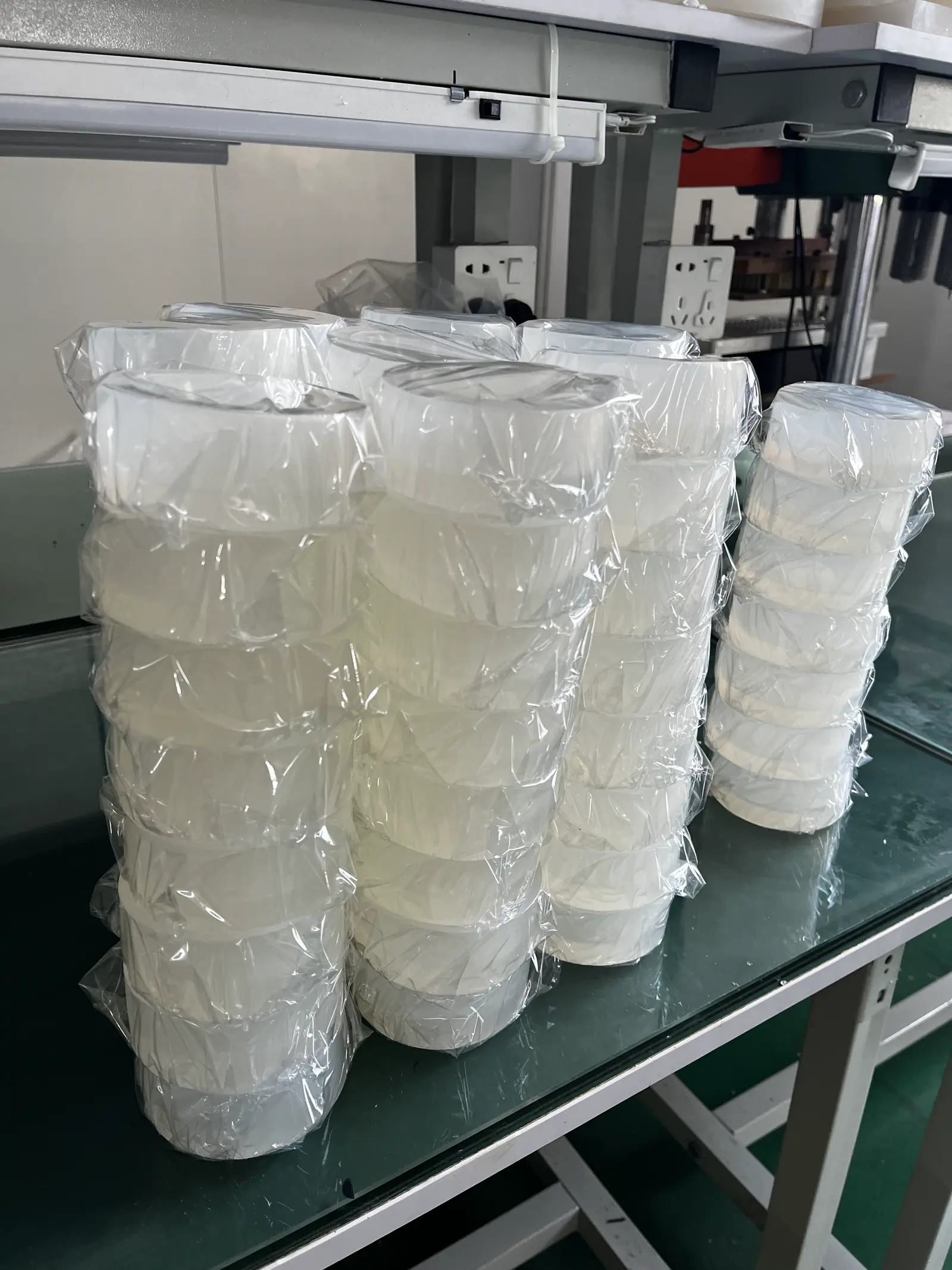 Stacks of bagged round silicone molds on a green packing table